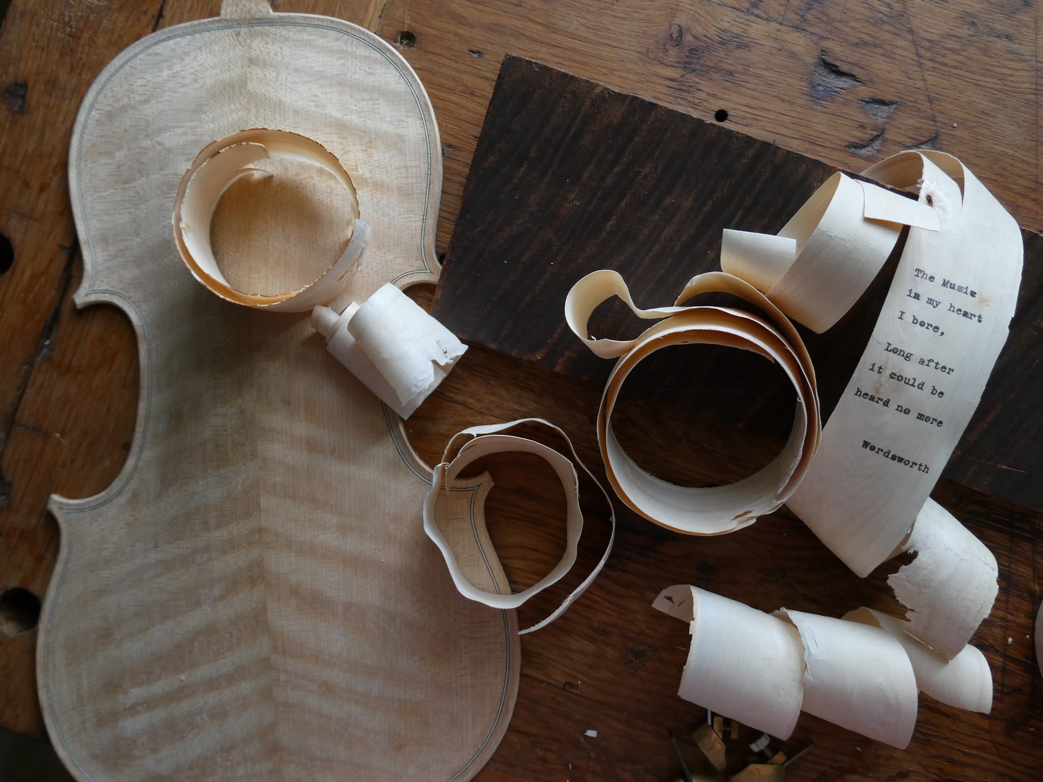 Violin body in progress with wood shavings bearing the Wordsworth verse