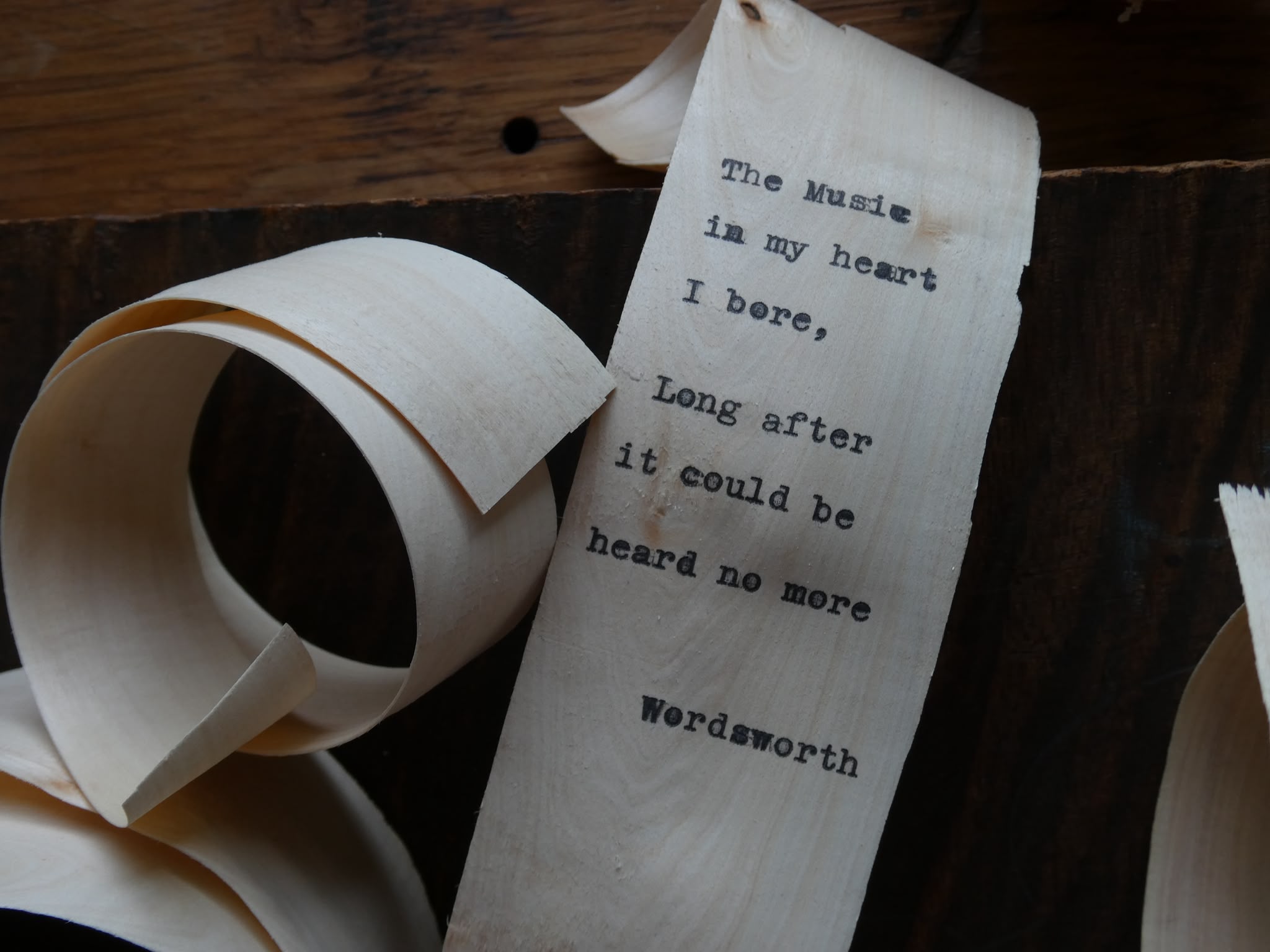 Close-up of Wordsworth verse typed onto a wood shaving: The Music in my heart I bore, Long after it could be heard no more